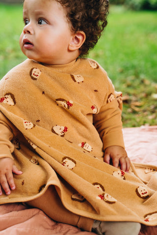 Boo Lätzchen mit Ärmeln Hedge Hugs: Kleinkind sitzt im Lätzchen auf einer Decke im Garten, von der Seite