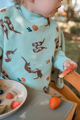 Boo Lätzchen mit Ärmeln Otter II: Kleinkind im Lätzchen am Tisch mit Erdbeeren, von der Seite