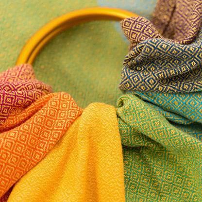 Warmer Schimmer und genialer Halt! Der handgewebte Ring Sling in den """"Gold Rainbow"""" Farben ist besonders griffig und ideal ab Geburt bis ins Kleinkindalter.""
