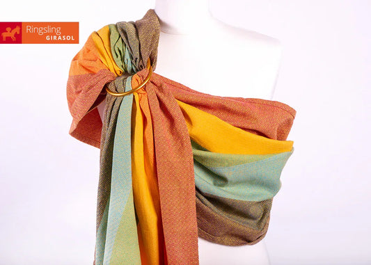 Warmer Schimmer und genialer Halt! Der handgewebte Ring Sling in den """"Gold Rainbow"""" Farben ist besonders griffig und ideal ab Geburt bis ins Kleinkindalter.""